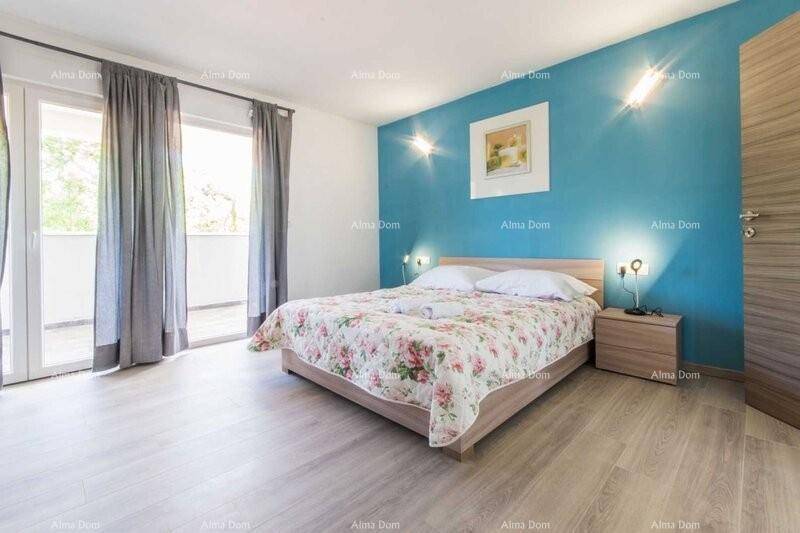 Helles Schlafzimmer mit blauer Akzentwand, Holzboden und Zugang zum Balkon.