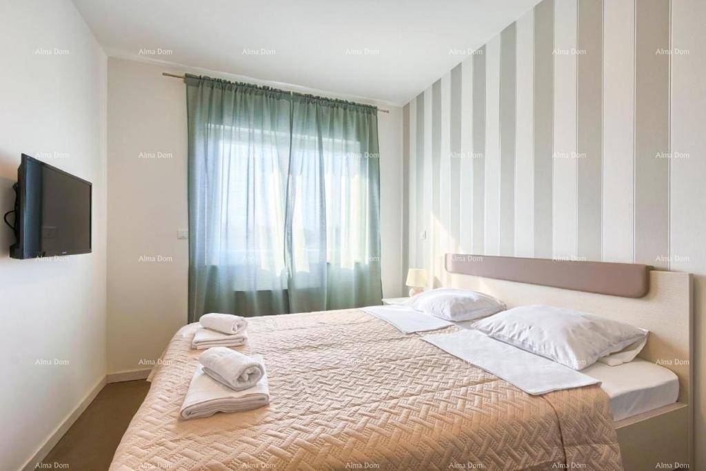 Gemütliches Schlafzimmer mit Doppelbett, gestreifter Tapete und Wandfernseher.