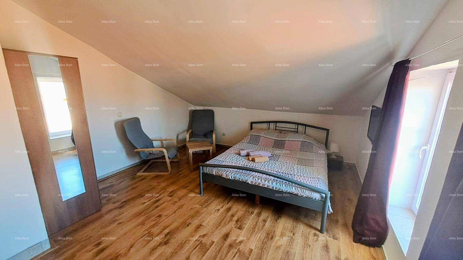 Helles Schlafzimmer mit Doppelbett, Kleiderschrank und Fenster im Dachgeschoss, mit Laminatboden.