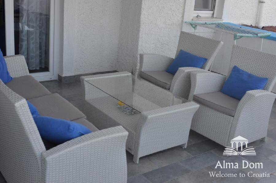 Heller Balkon mit weißen Korbmöbeln und blauen Kissen, ideal zum Entspannen.