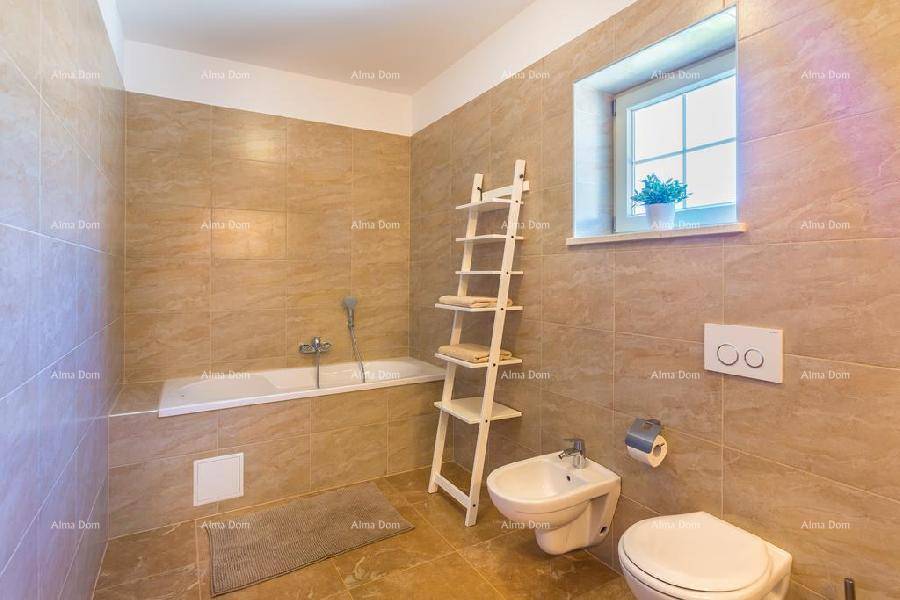 Geräumiges Badezimmer mit Badewanne, WC, Bidet und beigefarbenen Fliesen, die eine warme Atmosphäre schaffen.