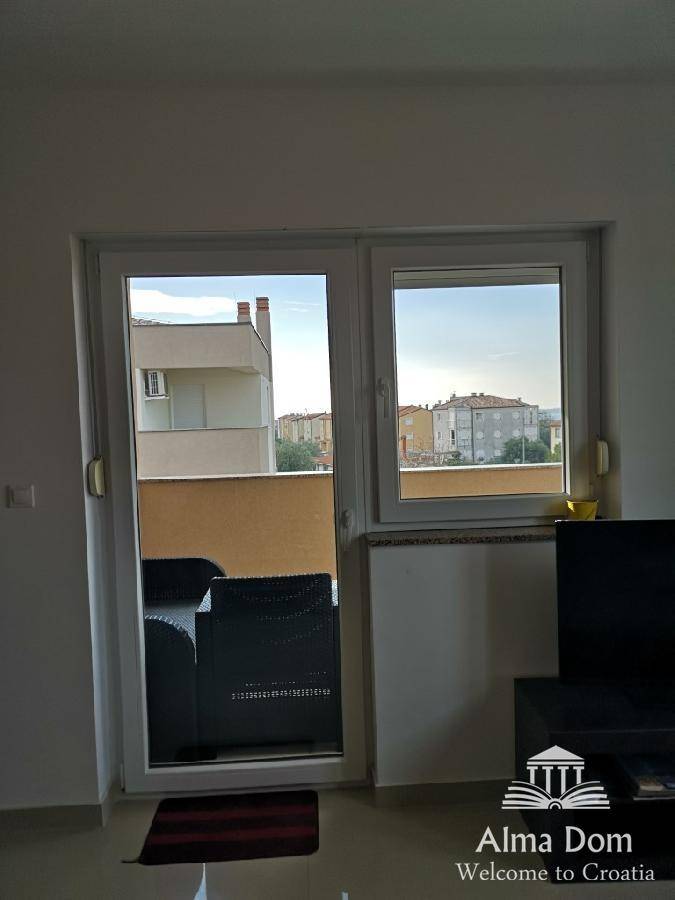 Blick aus dem Wohnzimmer auf den Balkon und die umliegenden Gebäude der Nachbarschaft.