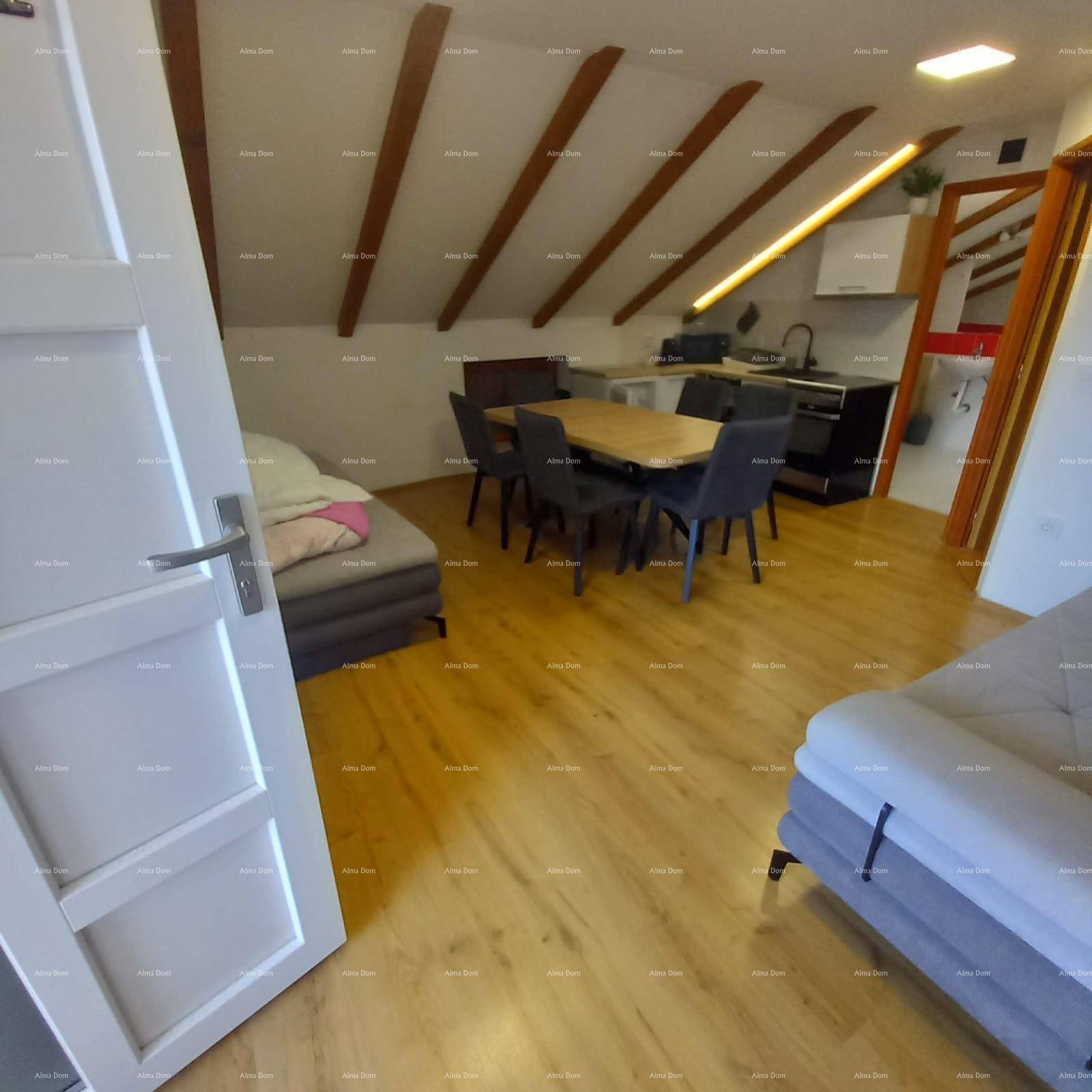 Offener Dachbodenbereich mit Essplatz, Küchenzeile und Schlafgelegenheiten unter Holzbalken.