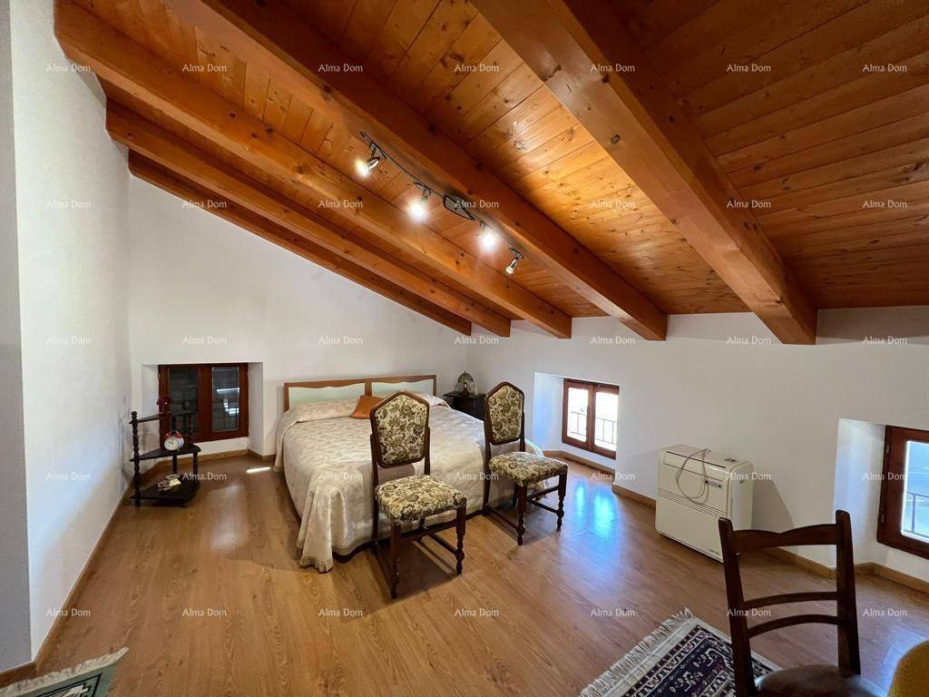 Helles Dachgeschoss-Schlafzimmer mit Holzbalken, Holzboden und kleinen Fenstern.