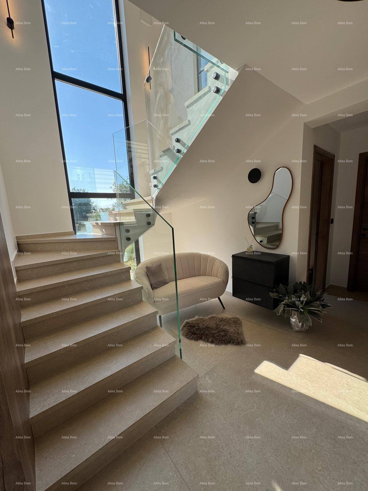 Elegante Treppe mit Glasgeländer und hohen Fenstern, die viel Tageslicht hereinlassen.