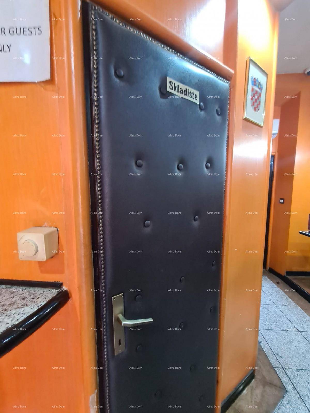 Gepolsterte Tür zu einem Lagerraum in einem Flur mit orangefarbenen Wänden und Fliesenboden.