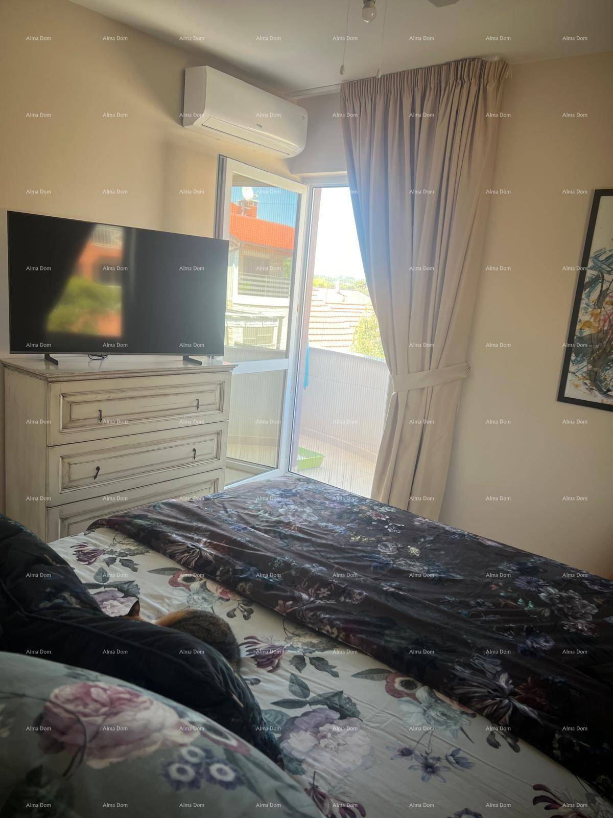 Helles Schlafzimmer mit floral gemustertem Bett und direktem Zugang zu einem Außenbereich, ausgestattet mit Klimaanlage.