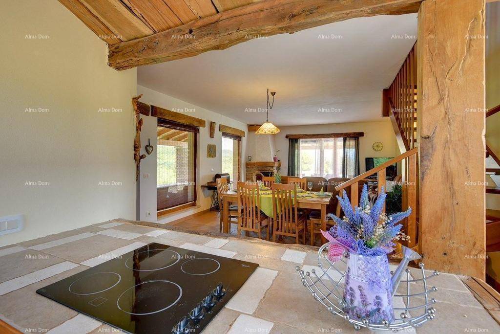 Küchenbereich mit Kochfeld und Blick auf den offenen Wohn- und Essbereich mit Holztisch und Treppe.