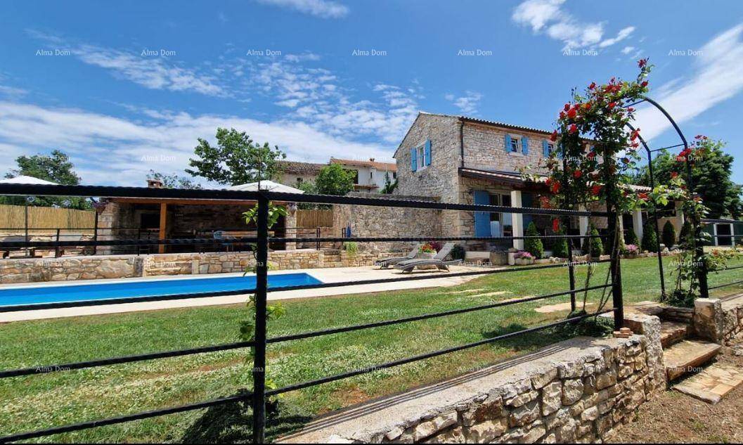 Weitläufiger Gartenbereich mit Pool, Steinhaus und dekorativem Zaun unter strahlend blauem Himmel.