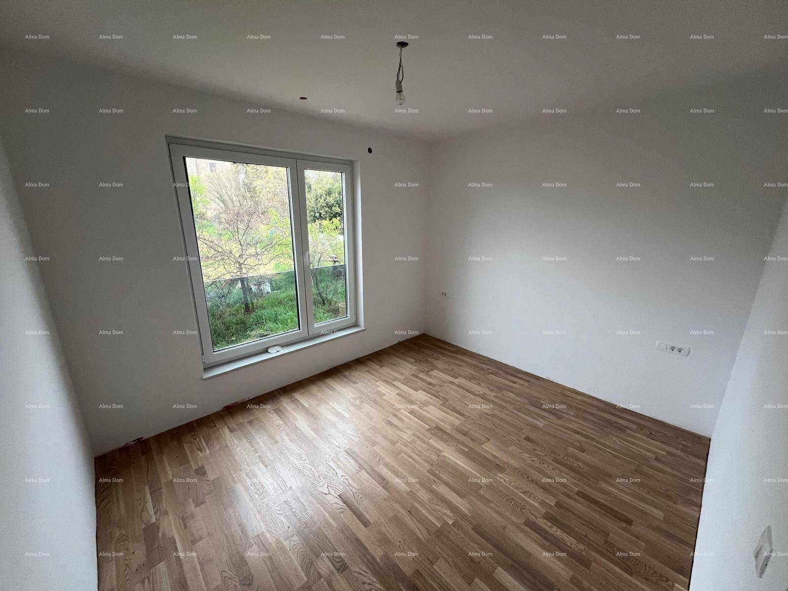 Helles Zimmer mit Parkettboden, weißen Wänden und einem Fenster mit Blick ins Grüne.