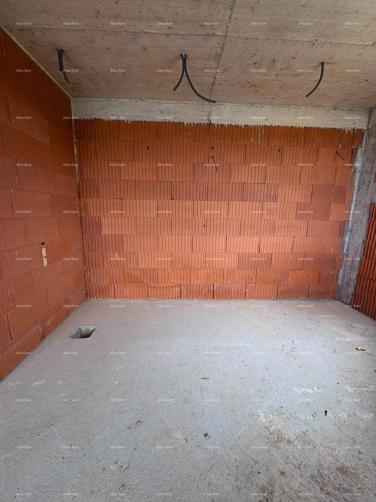 Rohbau eines Raumes mit Ziegelwänden, Betonboden und sichtbaren Elektroinstallationen.
