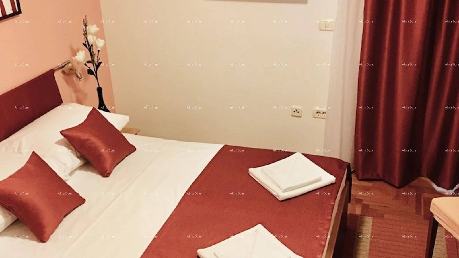 Schlafzimmer mit Doppelbett, roten Kissen und Vorhängen, sowie einem Holzboden und Tageslicht.