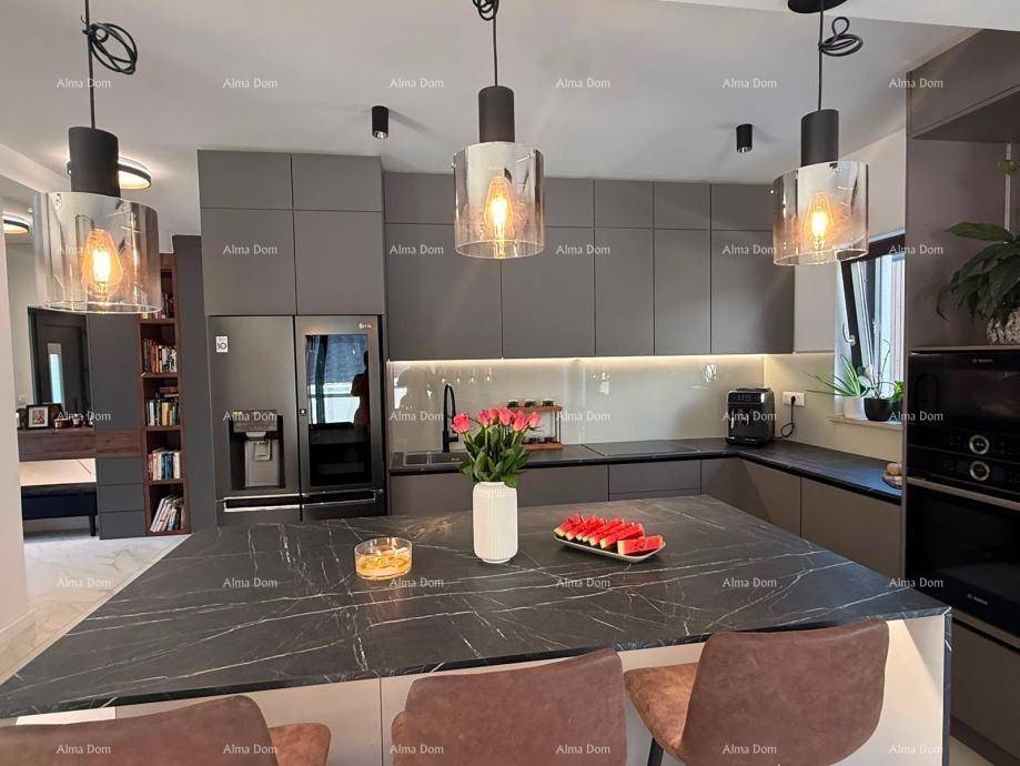 Moderne Küche mit grauen Schränken, großer Kücheninsel und stilvoller Beleuchtung, ideal zum Kochen.