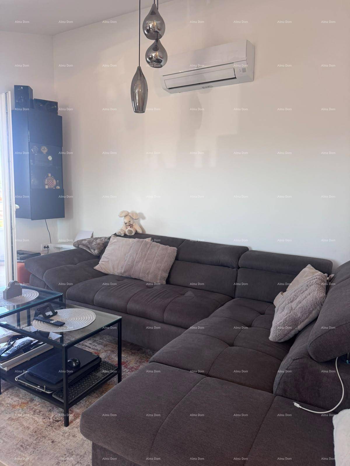 Helles Wohnzimmer mit großem Ecksofa, modernem Couchtisch und Klimaanlage an der Wand.