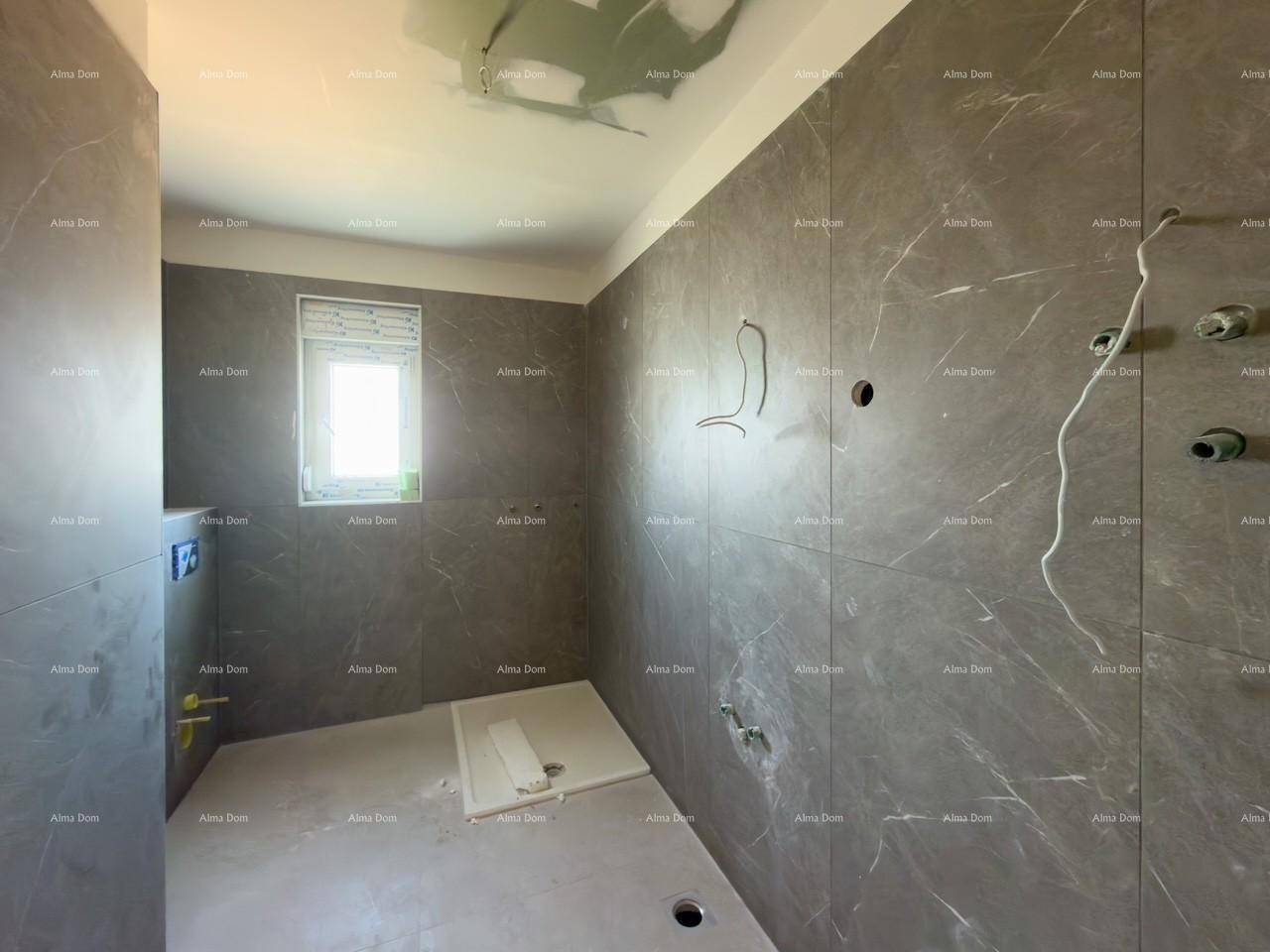 Unfertiges Badezimmer mit modernen grauen Fliesen und Fenster für Tageslicht.
