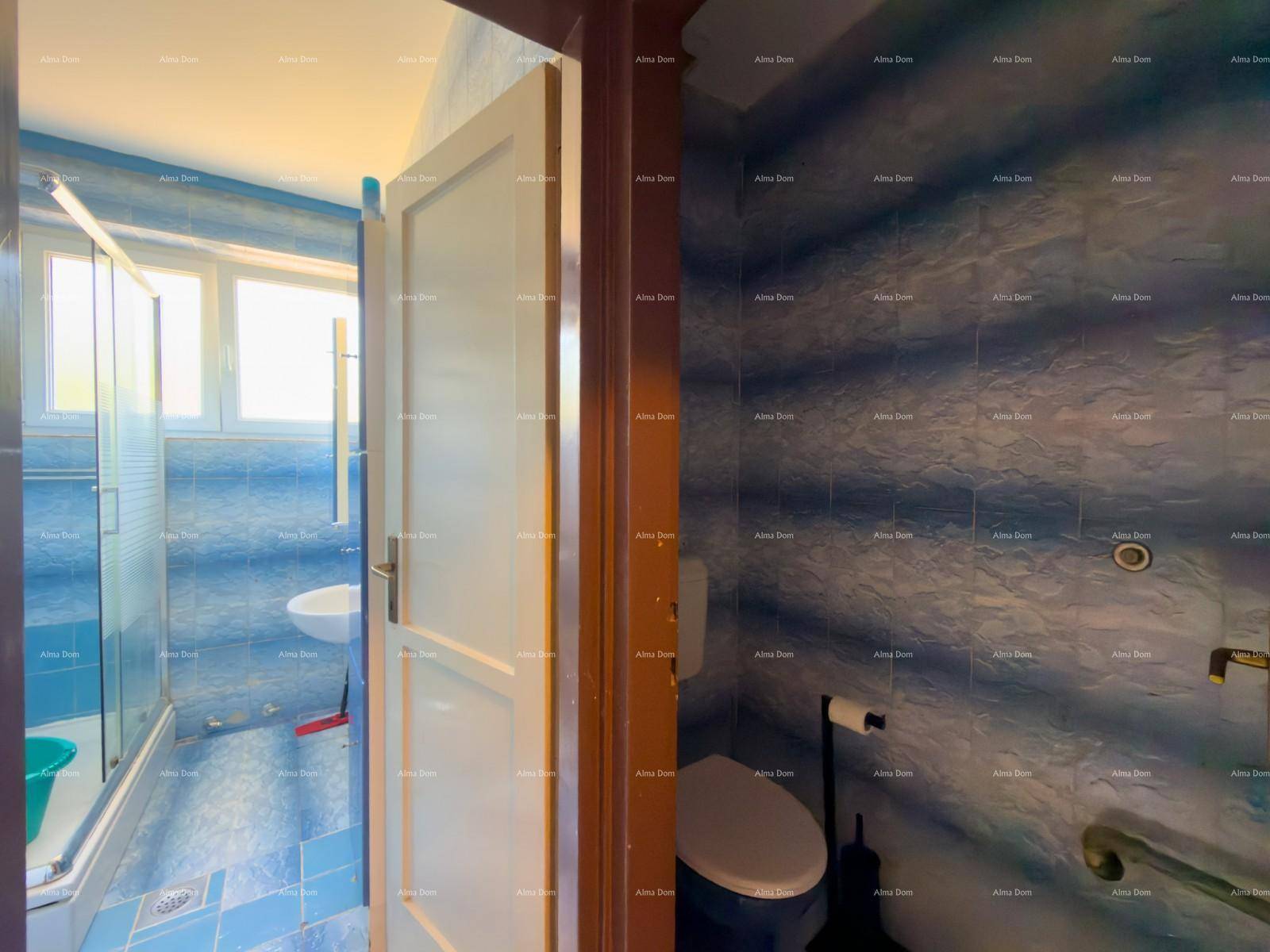 Badezimmer mit blauen Fliesen, Duschkabine und Fenster.