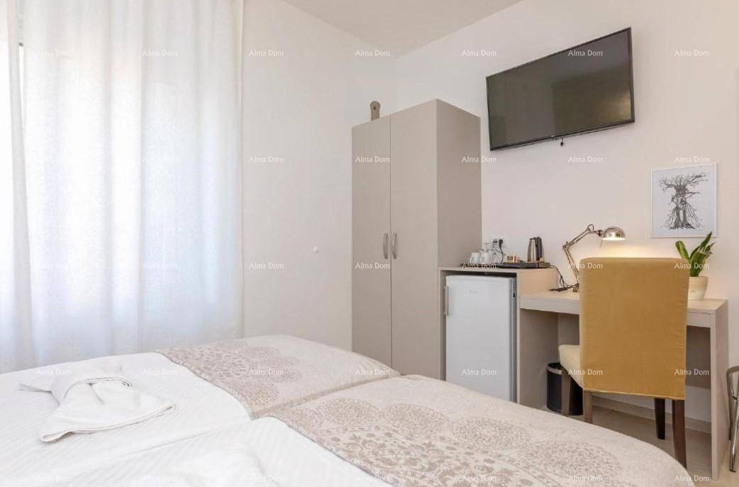 Schlafzimmer mit Kleiderschrank, Minibar, Schreibtisch und einem an der Wand montierten Fernseher.