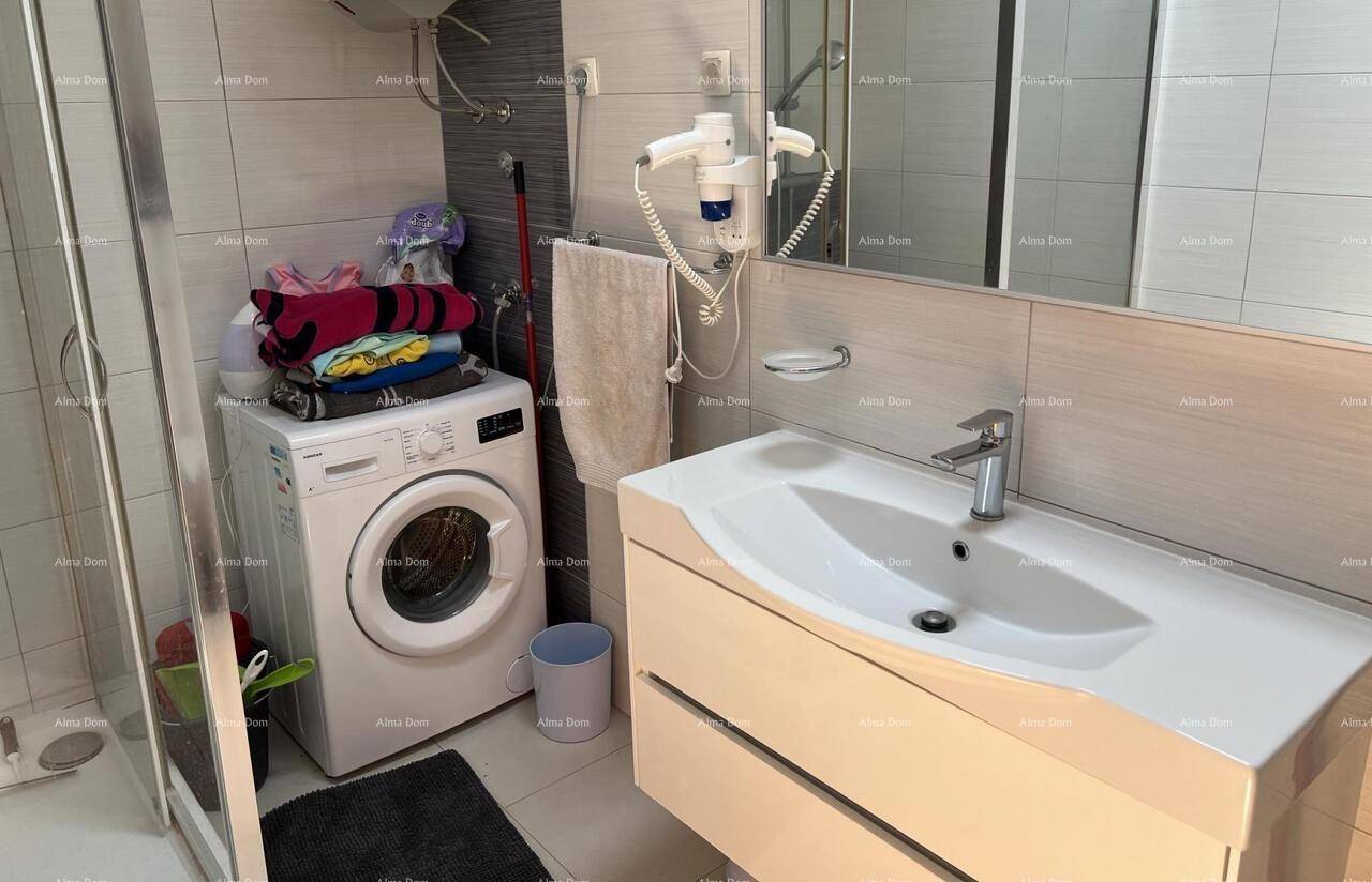 Badezimmer mit modernem Waschtisch, großem Spiegel und einer Waschmaschine unter einem Wandspiegel.
