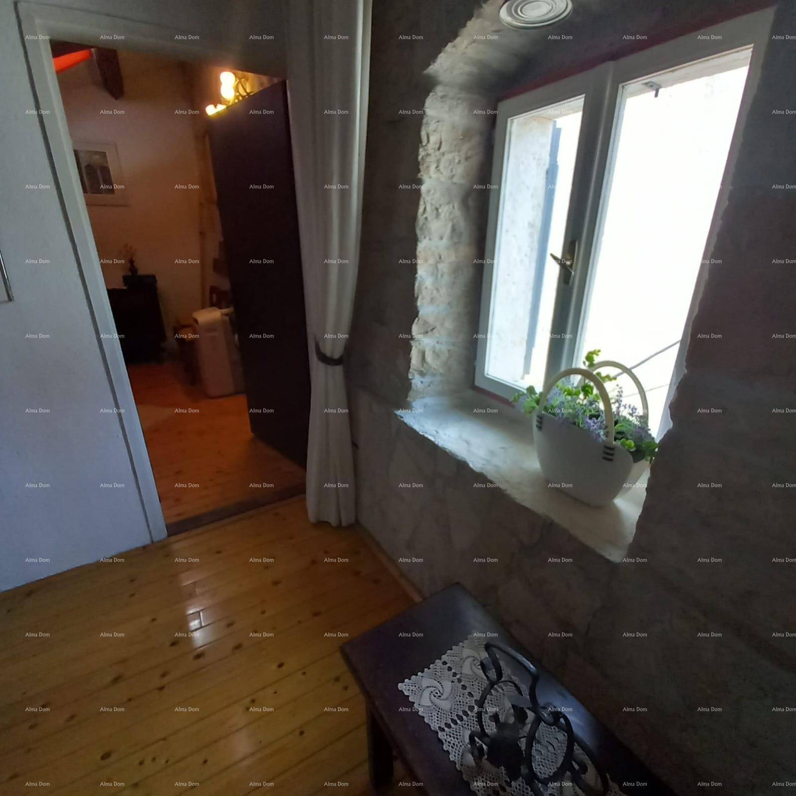 Innenraum mit Holzboden, Steinwand und einem Fenster, das viel Tageslicht hereinlässt.