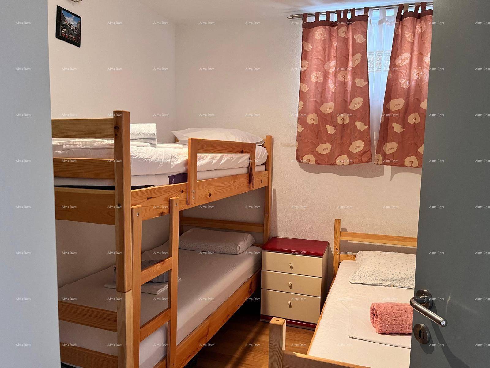 Schlafzimmer mit Etagenbetten und einem Einzelbett, ideal für mehrere Personen, mit Vorhängen am Fenster.
