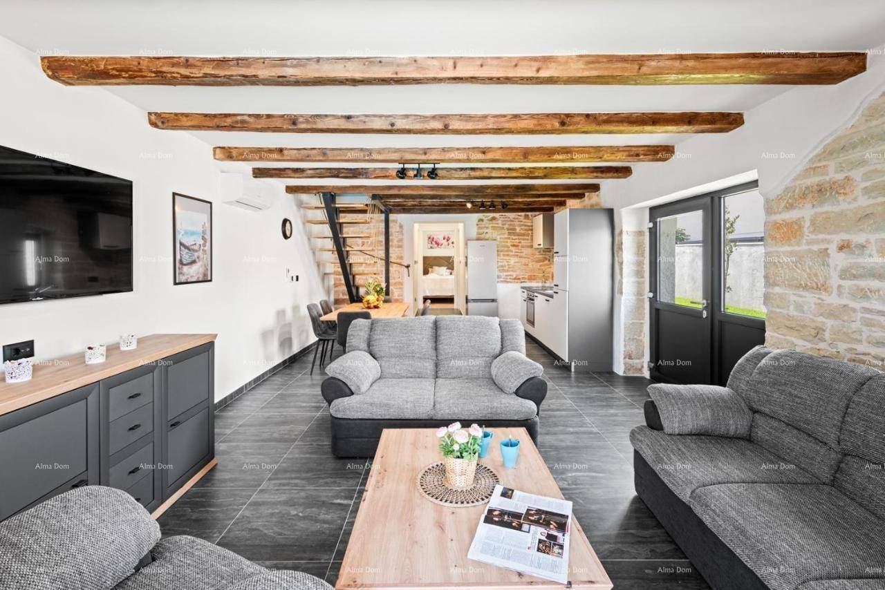 Gemütlicher Wohnbereich mit bequemen Sofas, Holzbalken und Blick auf den Essbereich und die offene Treppe.