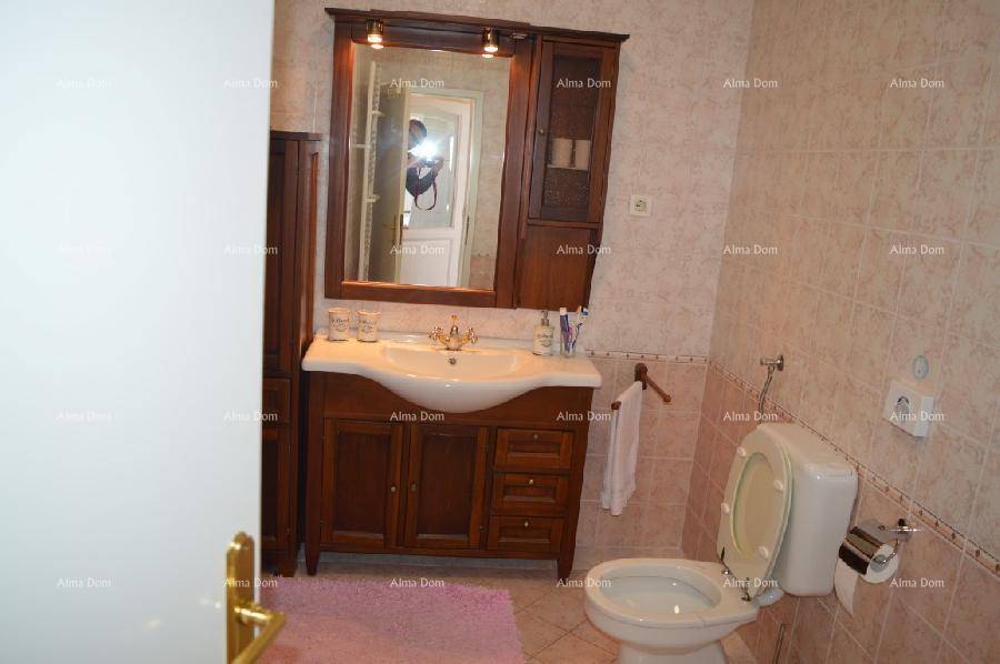 Badezimmer mit Holzwaschtisch, Spiegel und WC, ausgestattet mit beigen Fliesen.