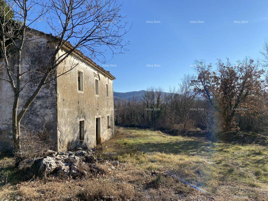 Verfallenes Steinhaus in einer weiten, sonnigen Landschaft mit Blick auf entfernte Hügel.