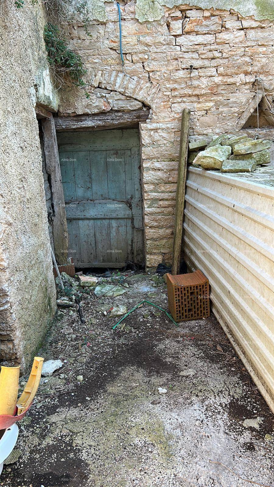 Alte Holztür in einer rustikalen Steinmauer mit unbefestigtem Vorplatz.