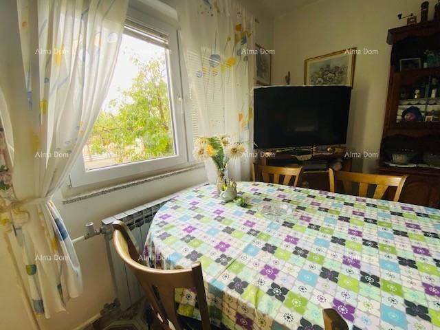 Essbereich mit großem Tisch, Stühlen und Blick durch das Fenster ins Grüne.