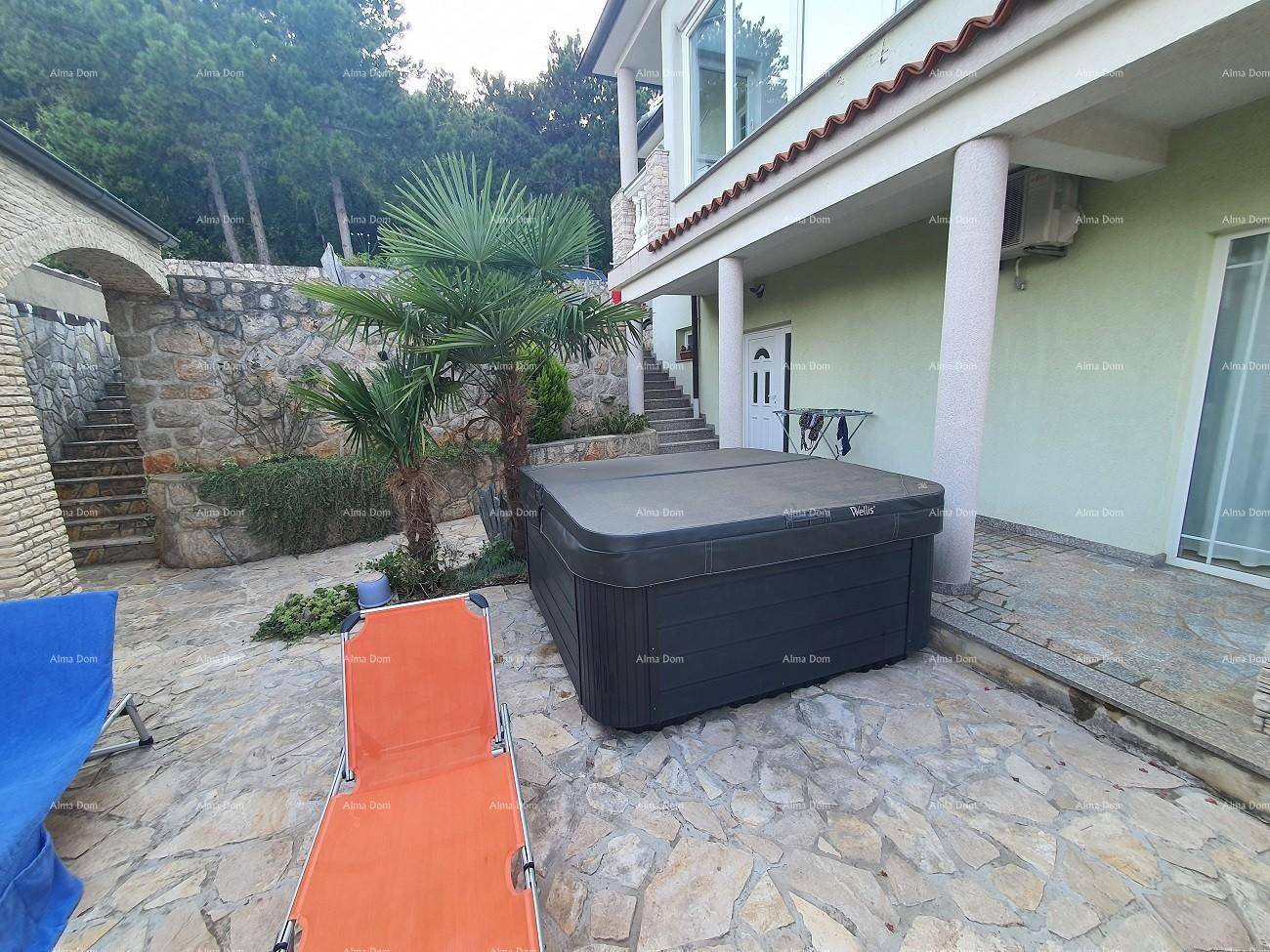 Gepflasterter Außenbereich mit Whirlpool und Liegestuhl, umgeben von Palmen und Steinmauern.