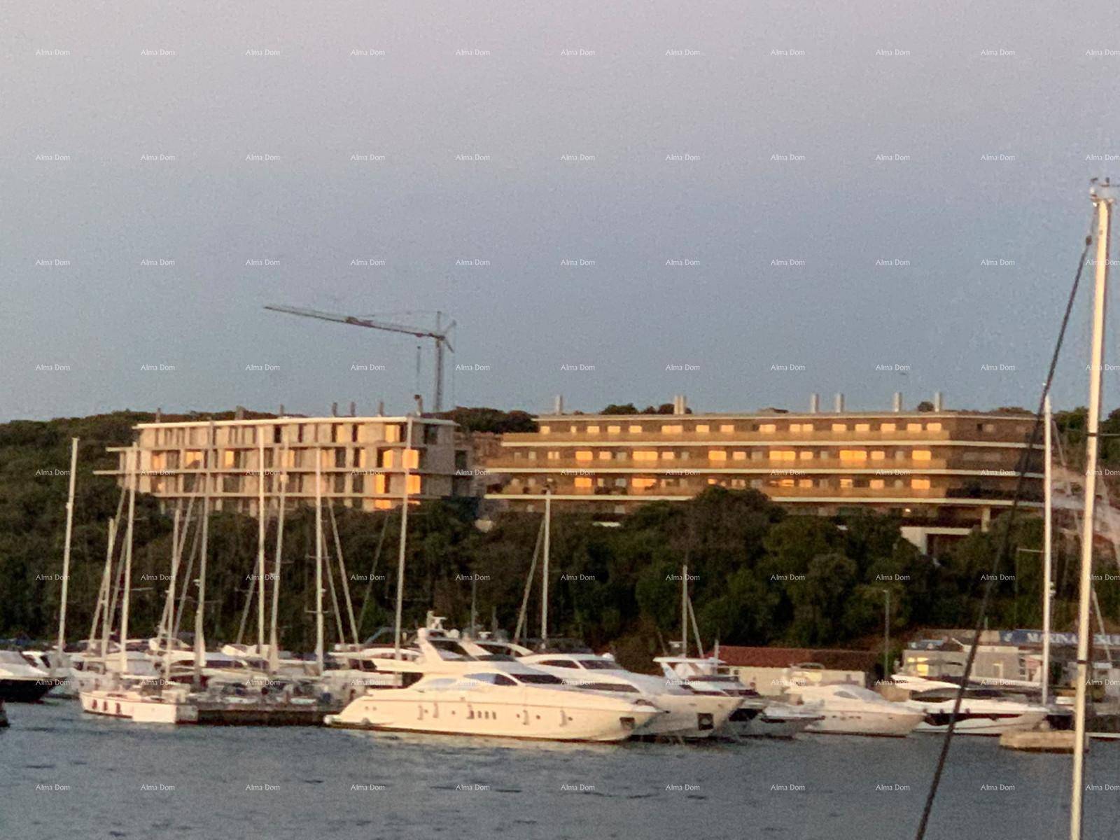 Panoramablick auf ein modernes Gebäude mit Balkonen und eine belebte Marina am Meer.