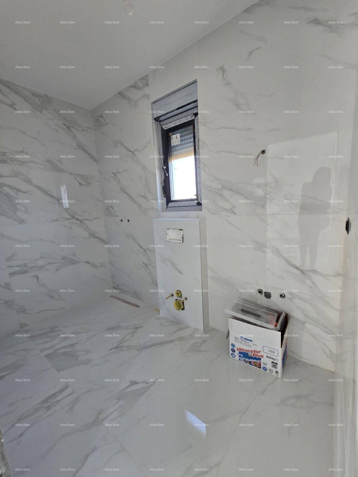Modernes Badezimmer im Rohbau mit großformatigen Marmorfliesen und Fenster für Tageslicht.