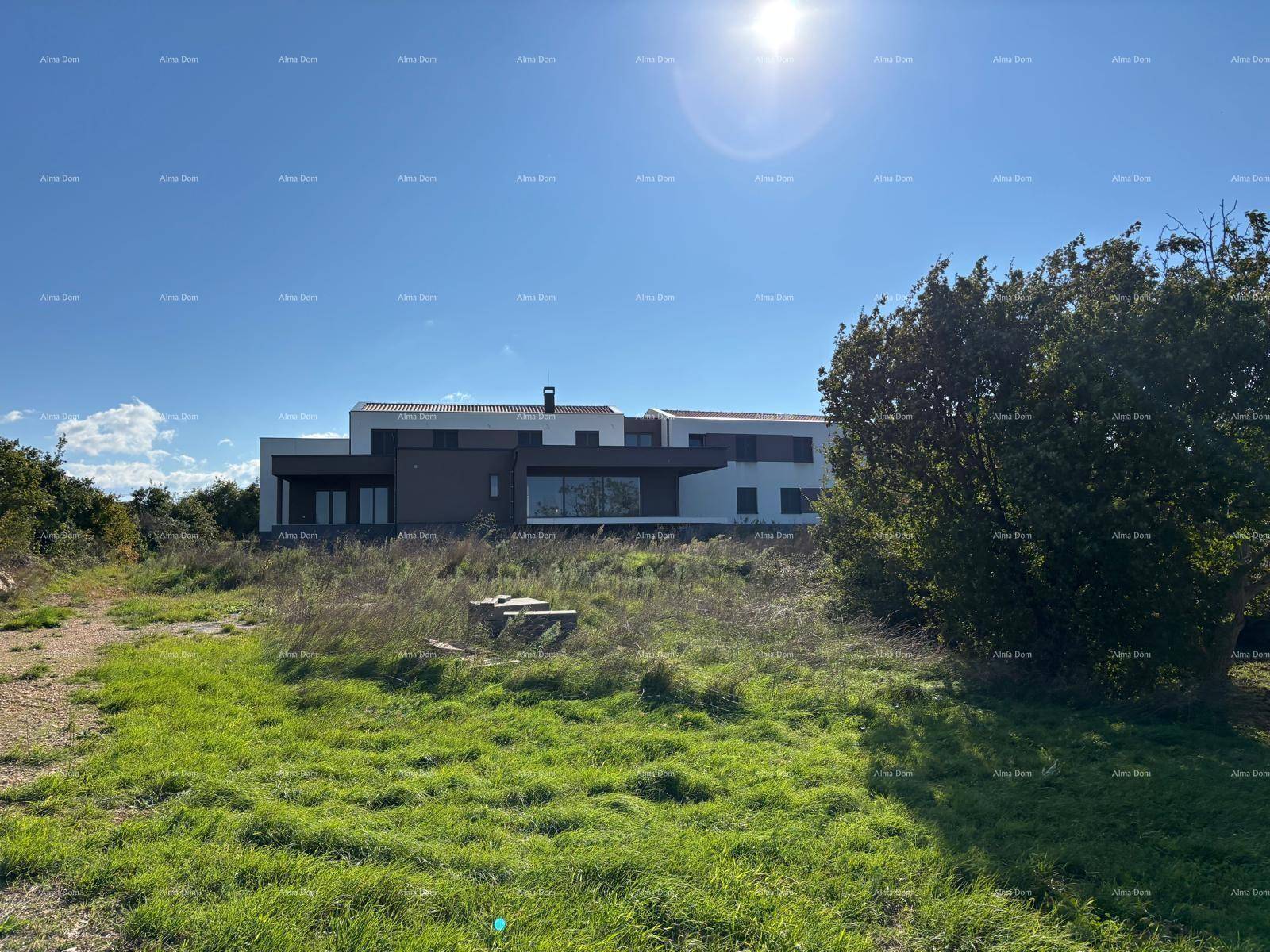 Blick auf das moderne Haus aus der Ferne, umgeben von unberührter Natur und grünen Feldern.