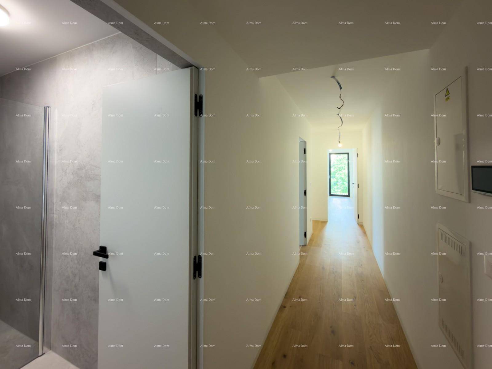 Heller Flur mit Holzboden und weißen Wänden, führt zu weiteren Räumen und einem Fenster am Ende.