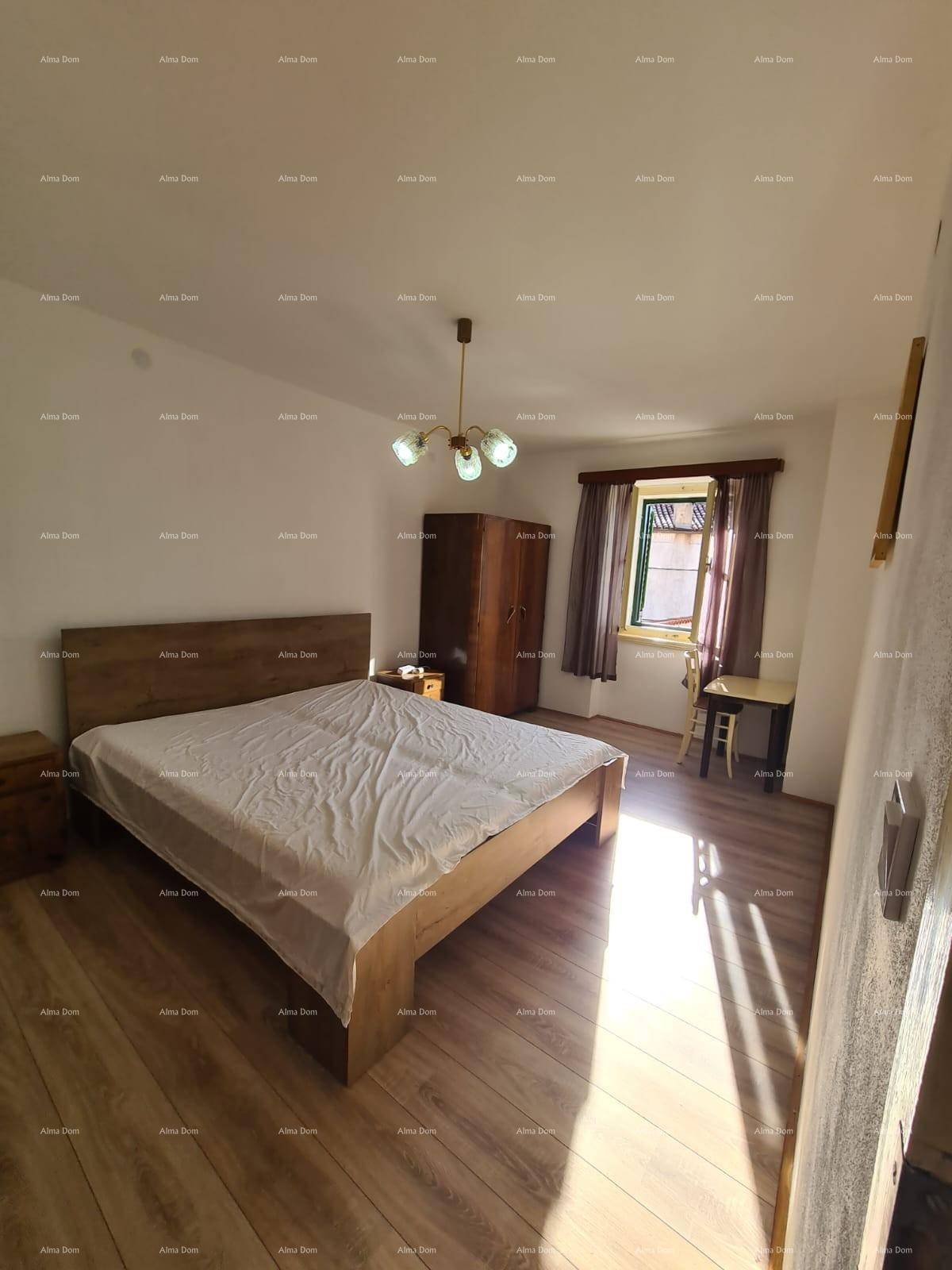 Geräumiges Schlafzimmer mit Doppelbett, Holzschrank und sonnigem Fensterbereich.