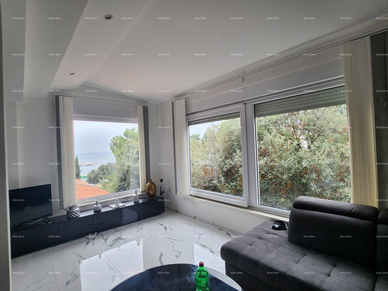 Helles Wohnzimmer mit großen Fenstern, modernem Sofa und Blick auf das Meer und viel Grün.