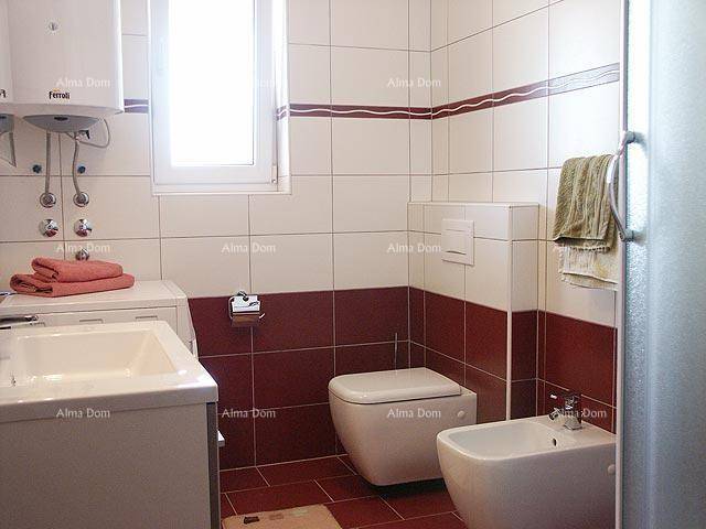 Modernes Badezimmer mit Toilette, Bidet, Waschbecken und rot-weißen Fliesen.