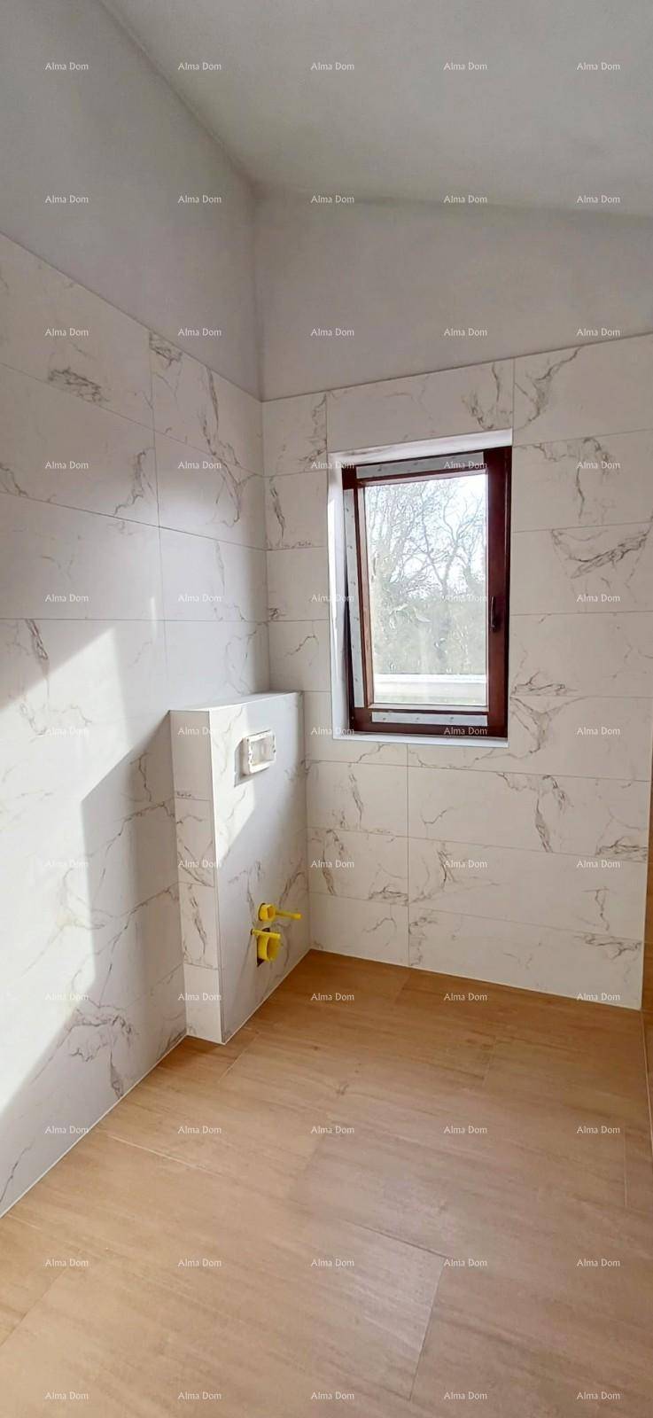 Schlafzimmer im Rohbau mit Holzboden, Akzentwand und Fenster für natürliches Licht.