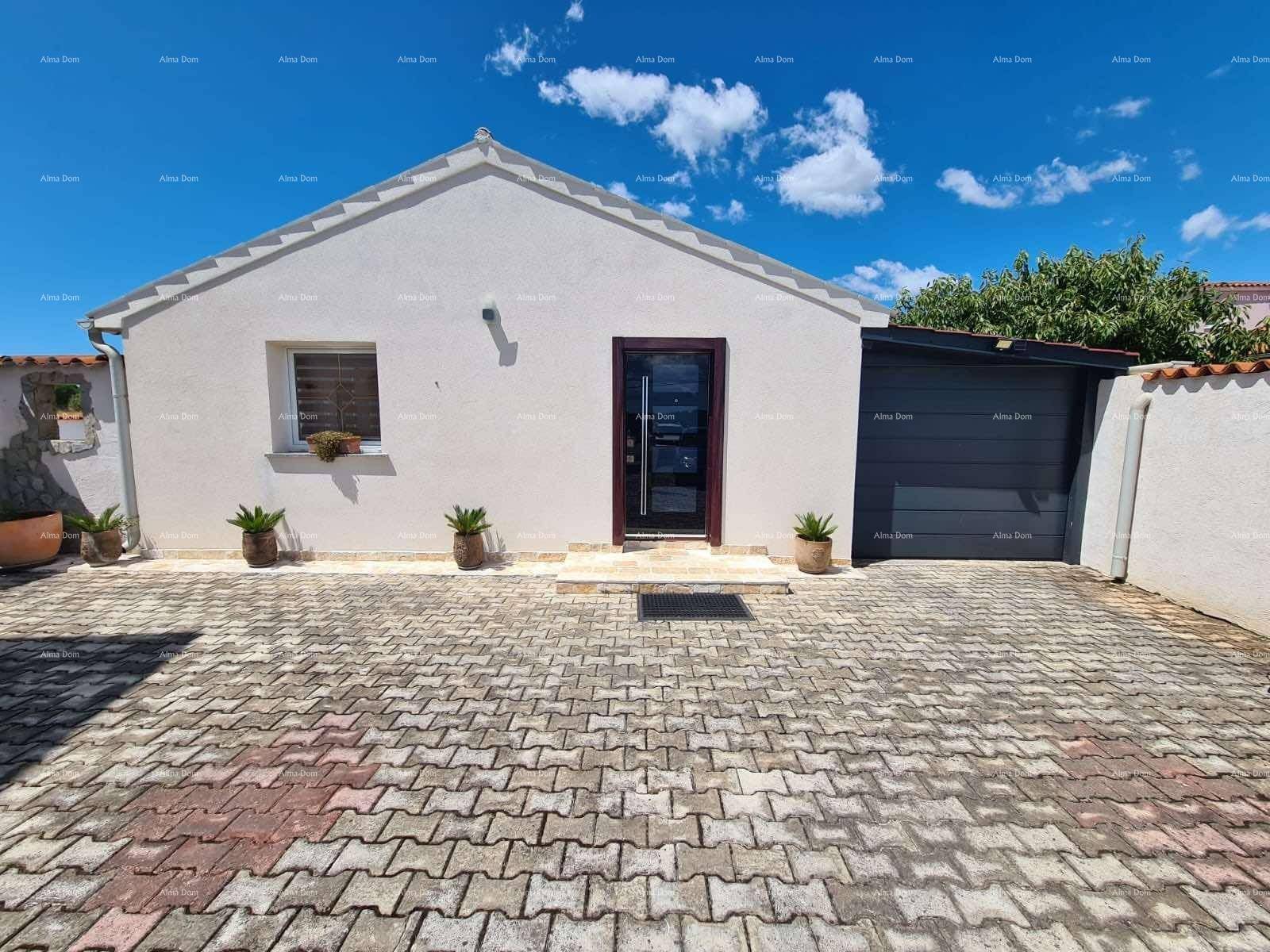 Vorderansicht eines Einfamilienhauses mit Garage und gepflastertem Vorplatz.