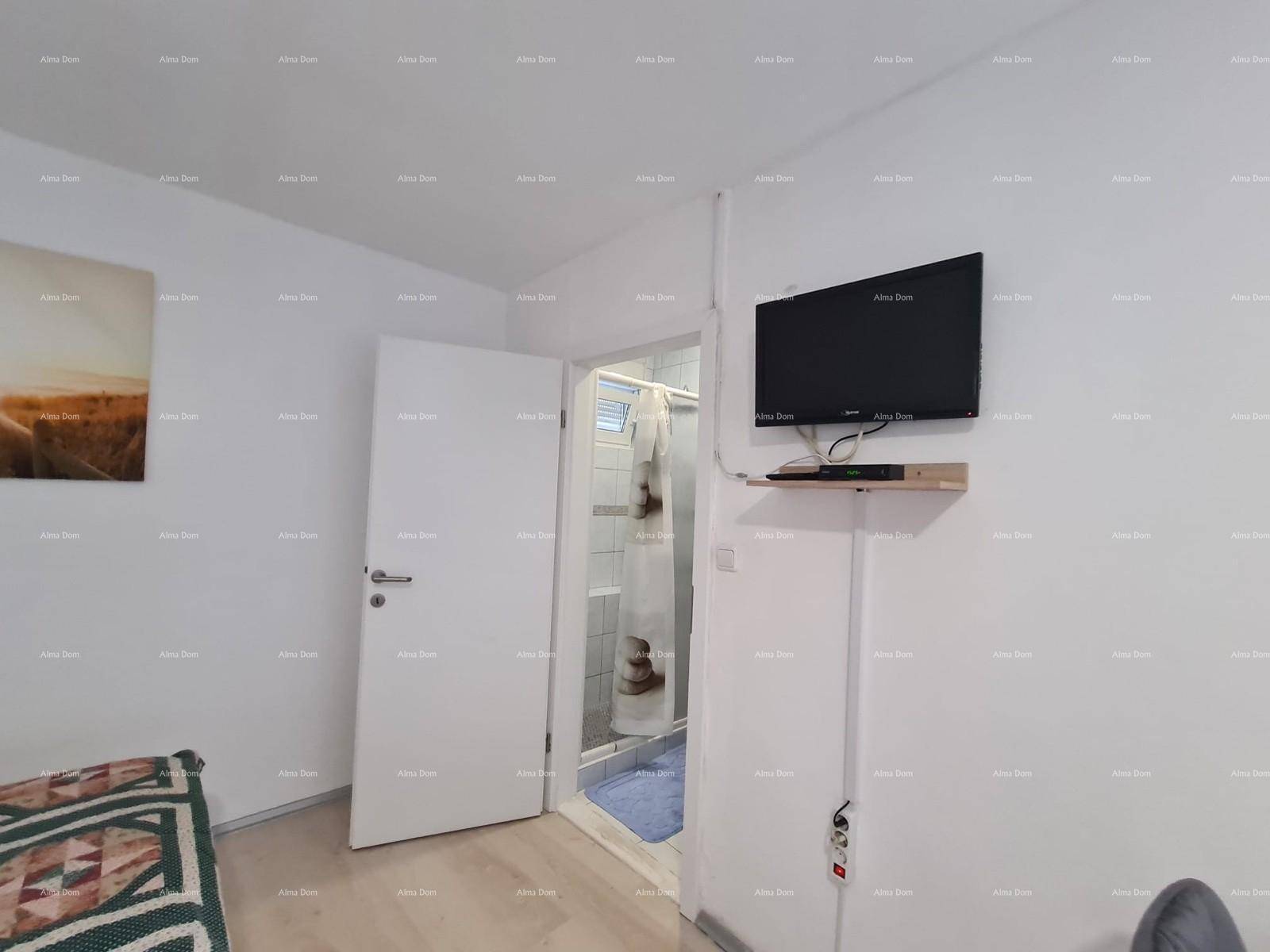 Schlafzimmer mit Wandfernseher und Zugang zu einem Badezimmer mit Duschkabine.