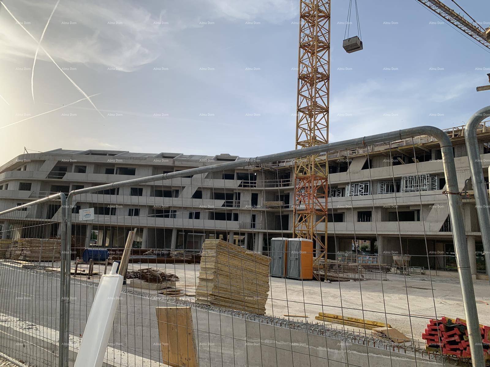 Baustelle der Wohnanlage im Rohbauzustand mit sichtbarer Betonstruktur und Baukran.