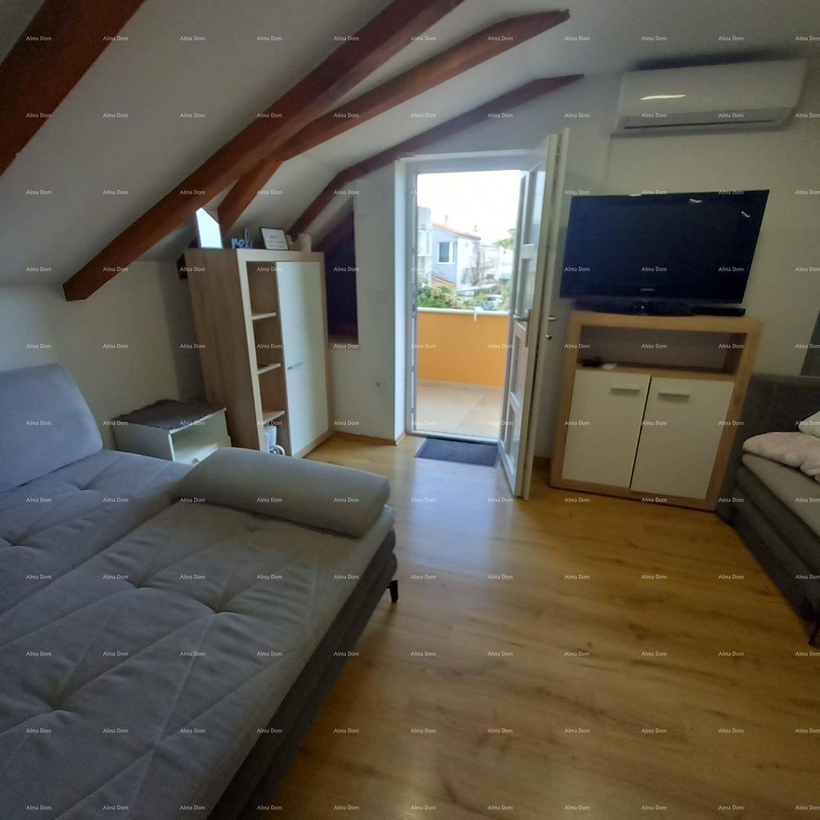 Geräumiger Dachbodenraum mit sichtbaren Holzbalken, Laminatboden und Schlafsofa.
