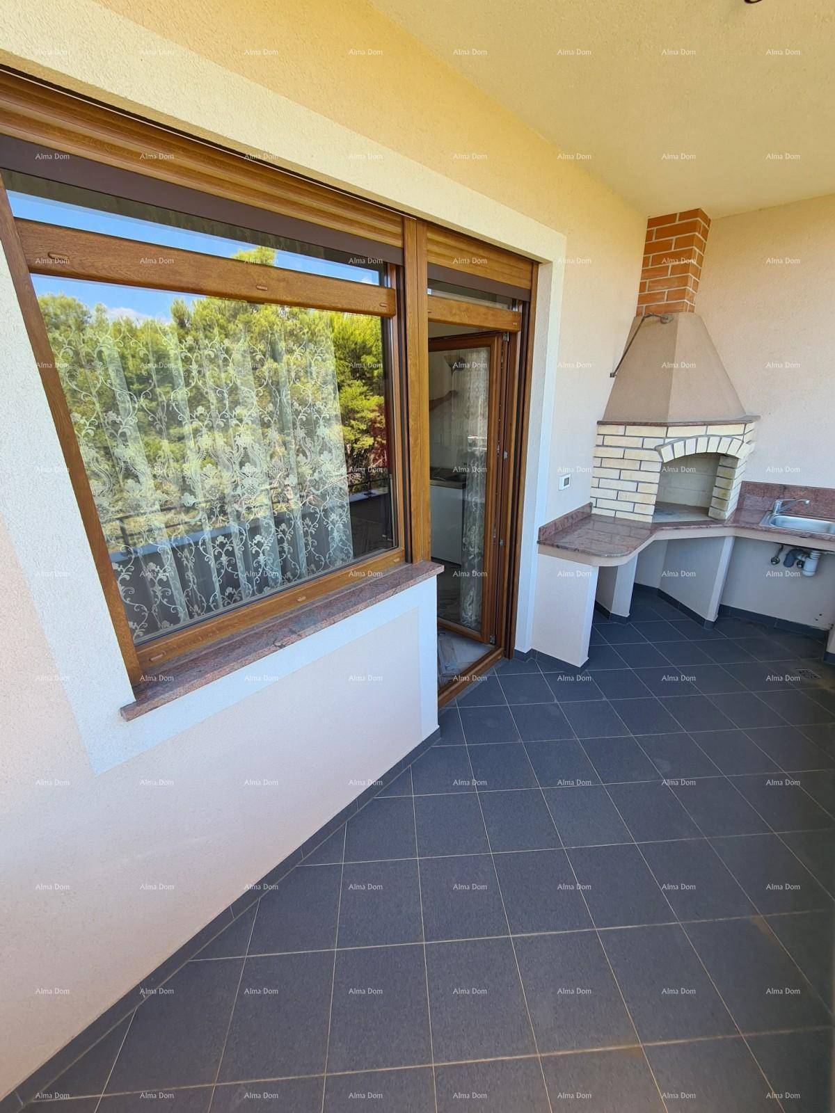 Balkon mit Außenküche und Zugang zum Innenbereich durch eine große Glastür.