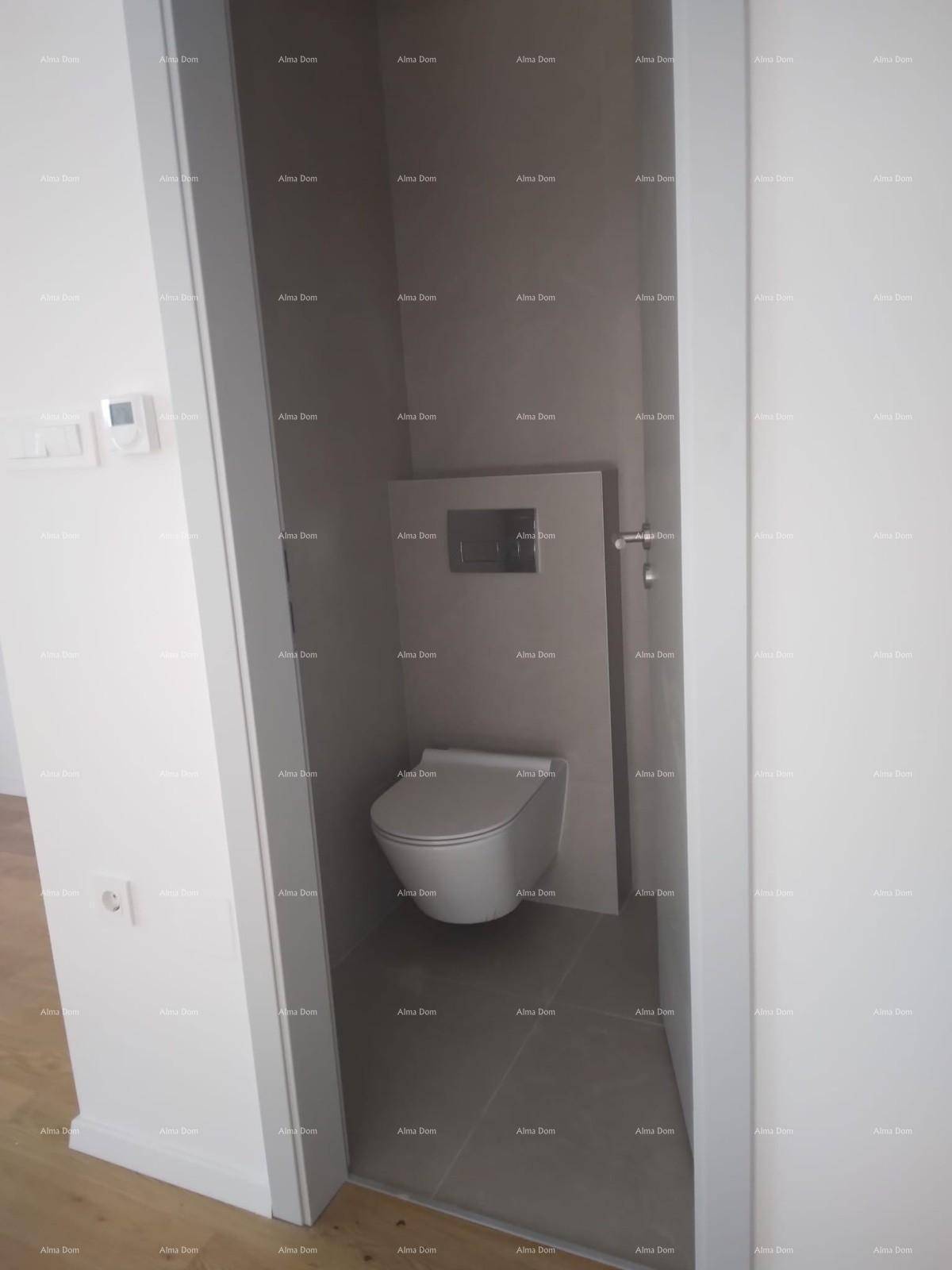 Separates WC mit wandhängender Toilette und modernen grauen Fliesen.