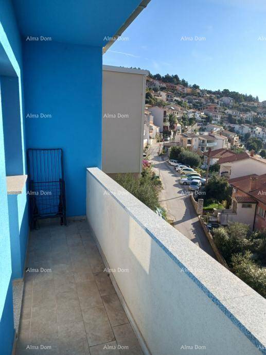 Balkon mit blauer Wand und weißem Geländer, bietet einen Blick auf die Straße und die Häuser am Hang.