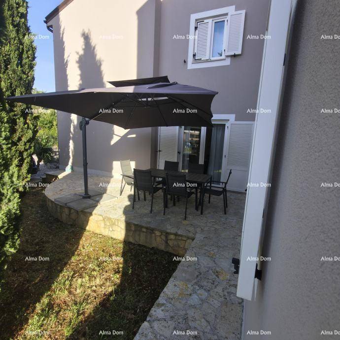 Außenbereich mit möblierter Terrasse, Sonnenschirm und angrenzendem Garten.