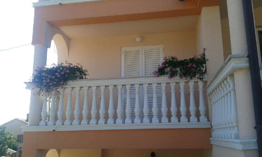 Balkon mit dekorativer Balustrade und blühenden Pflanzen, der eine angenehme Atmosphäre schafft. 