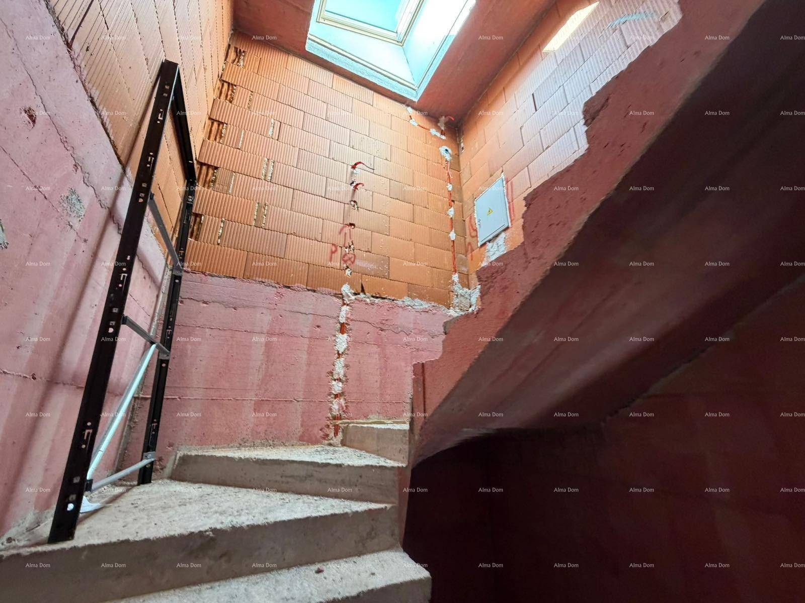 Treppenhaus im Rohbau mit Betontreppen, unverputzten Ziegelwänden und einem Oberlicht für Helligkeit.