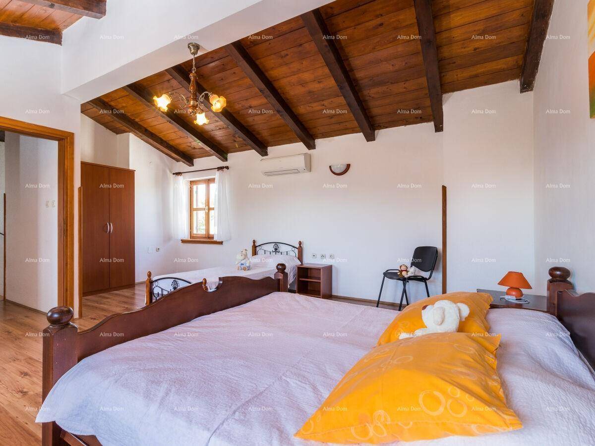 Helles Schlafzimmer mit Holzbalkendecke, Holzboden und Blick nach draußen.