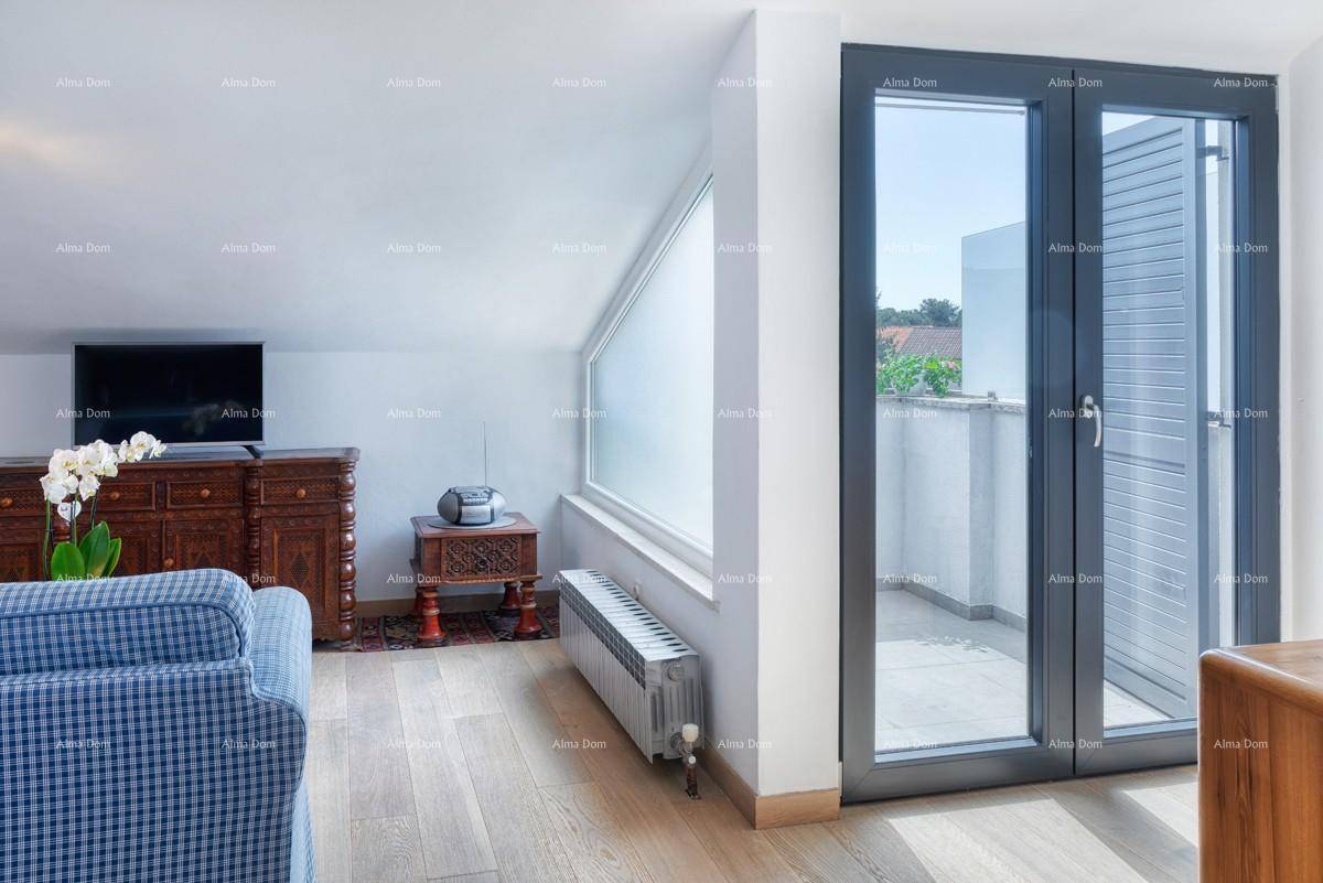 Wohnzimmer im Dachgeschoss mit Holzboden und Zugang zu einem kleinen Balkon.